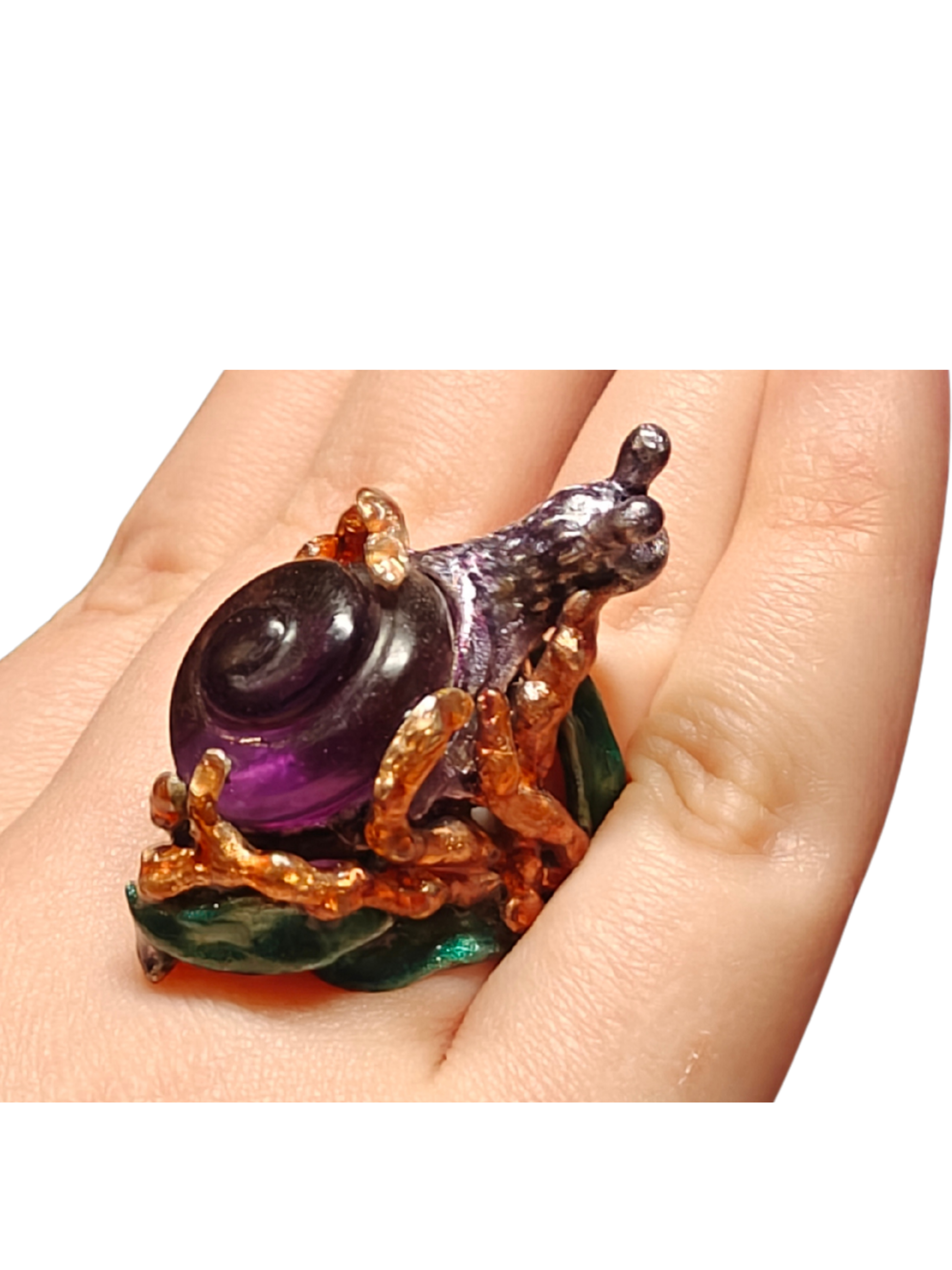 Close-up of the Amethyst Wanderer ring worn on a hand from the Stone Garden Collection by Konforti Jewelry, handcrafted in 960 silver and set with a 29 ct lab-grown amethyst carved into a spiral snail shell, detailed with hand-painted Limoges-style enamel in vivid layered colors.