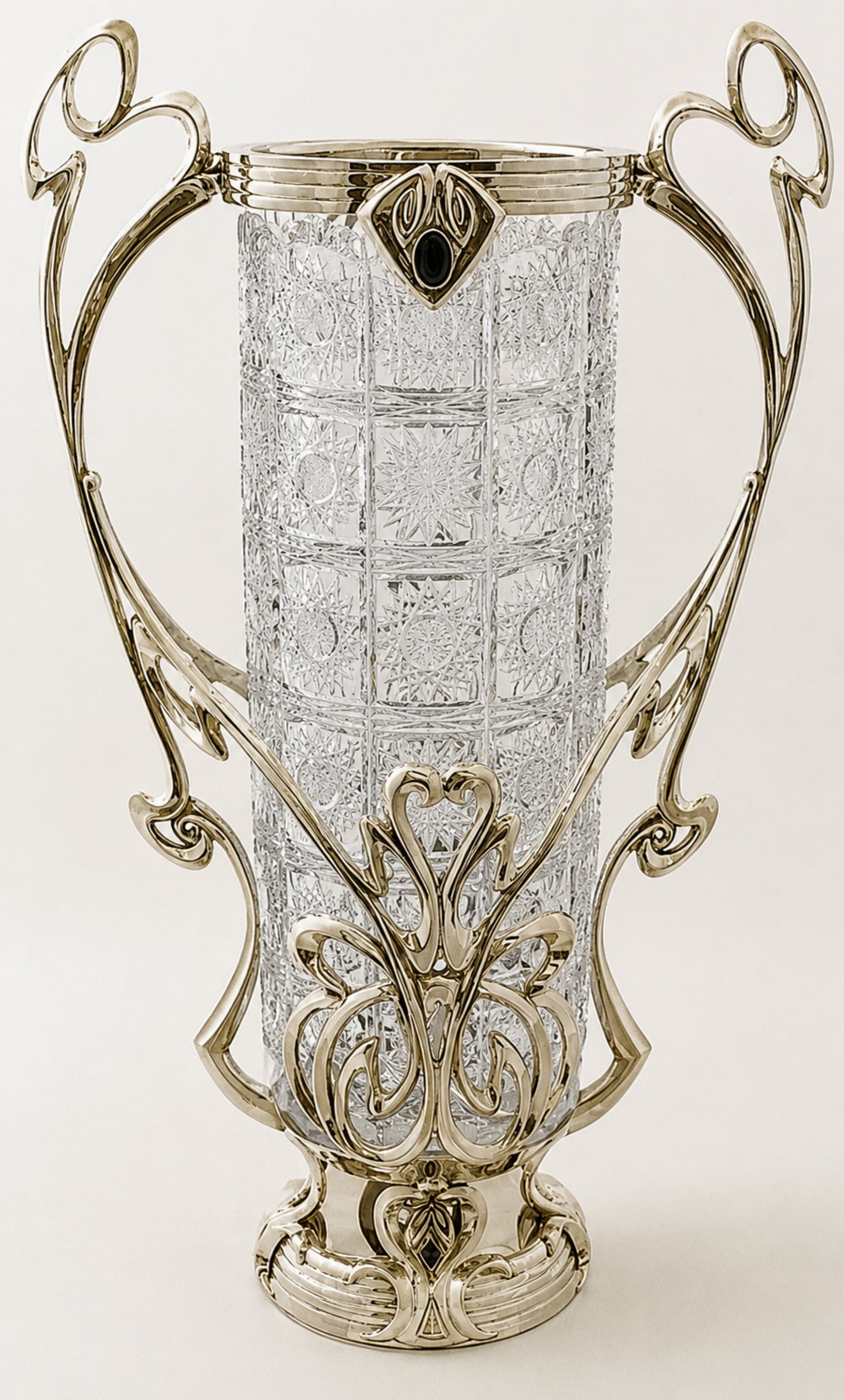An ornate Art Deco style vase featuring a clear cut-glass cylindrical body and an elaborate silver-toned metal frame with scrollwork and a decorative base.