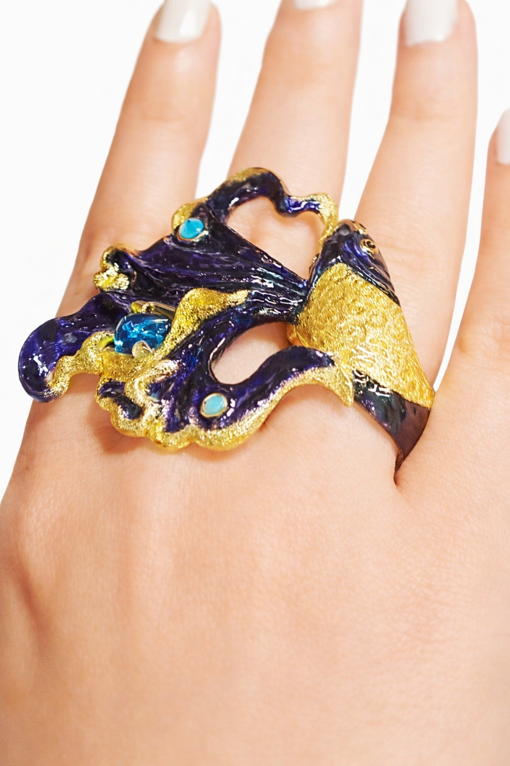 Statement betta fish cocktail ring worn on hand with sculptural flowing enamel fins and blue topaz gemstone in collectible artisan jewelry design.