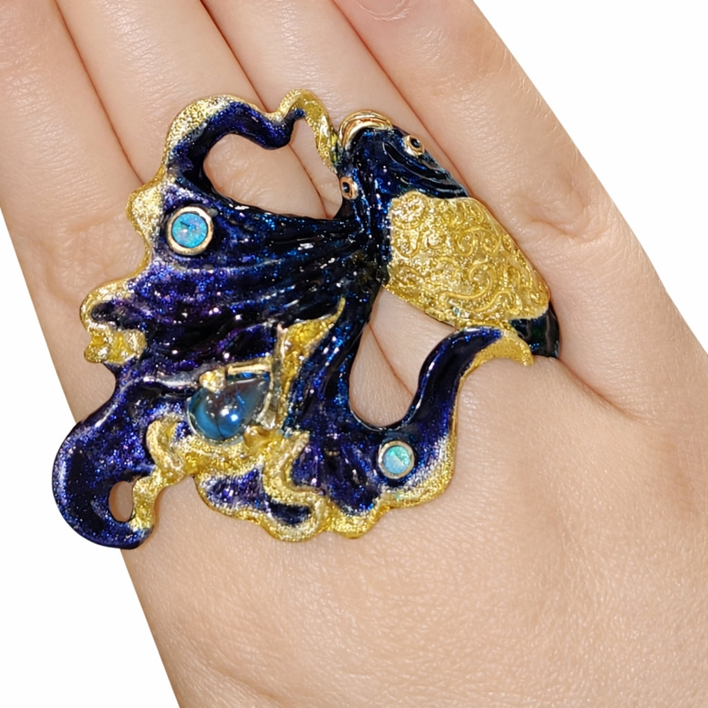 Close-up detail of luxury betta fish ring showing blue topaz centerpiece, opal accents and textured gold-tone enamel over sculpted 960 silver.