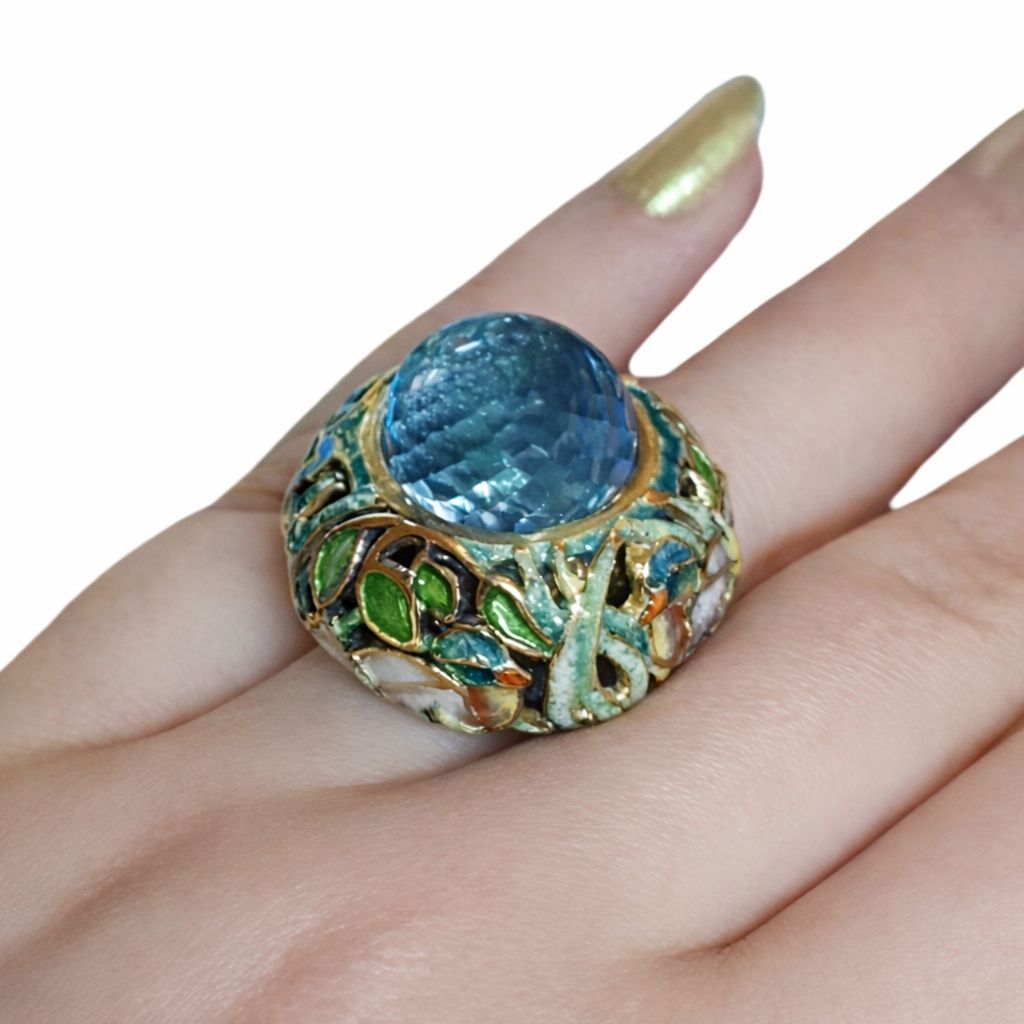 Angled on-hand view of the Shimmering Pond ring showing the depth of the Swiss topaz and the organic enamel garden design