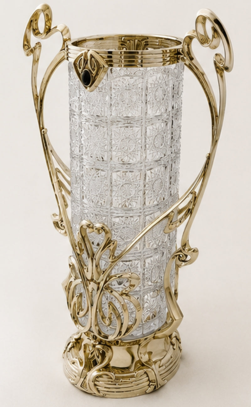 An ornate trophy cup with a textured clear glass body and elaborate polished gold-tone metal handles and base, photographed against a plain light background.