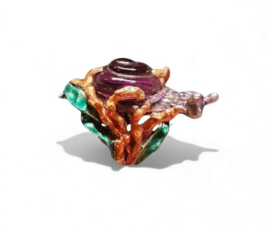 Angled image of the Amethyst Wanderer ring showcasing the detailed carving of the 29ct lab-grown amethyst snail shell and the vibrant layered enamel artwork decorating the 960 silver ring base.