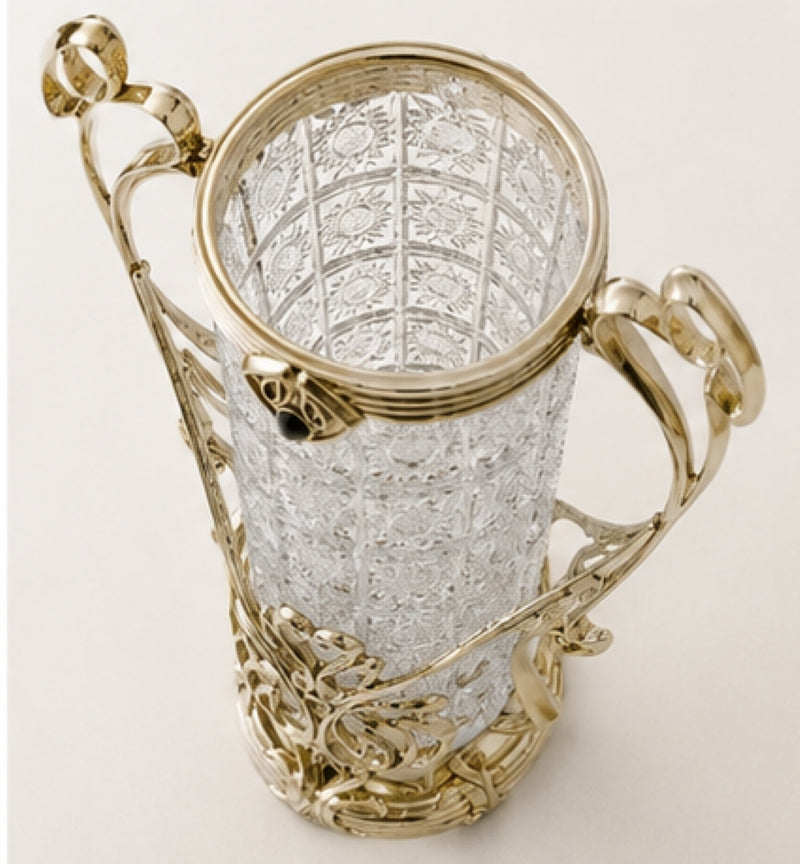 An ornate clear cut-glass goblet with polished gold-tone metal handles, rim, and decorative base, photographed on a clean light background.