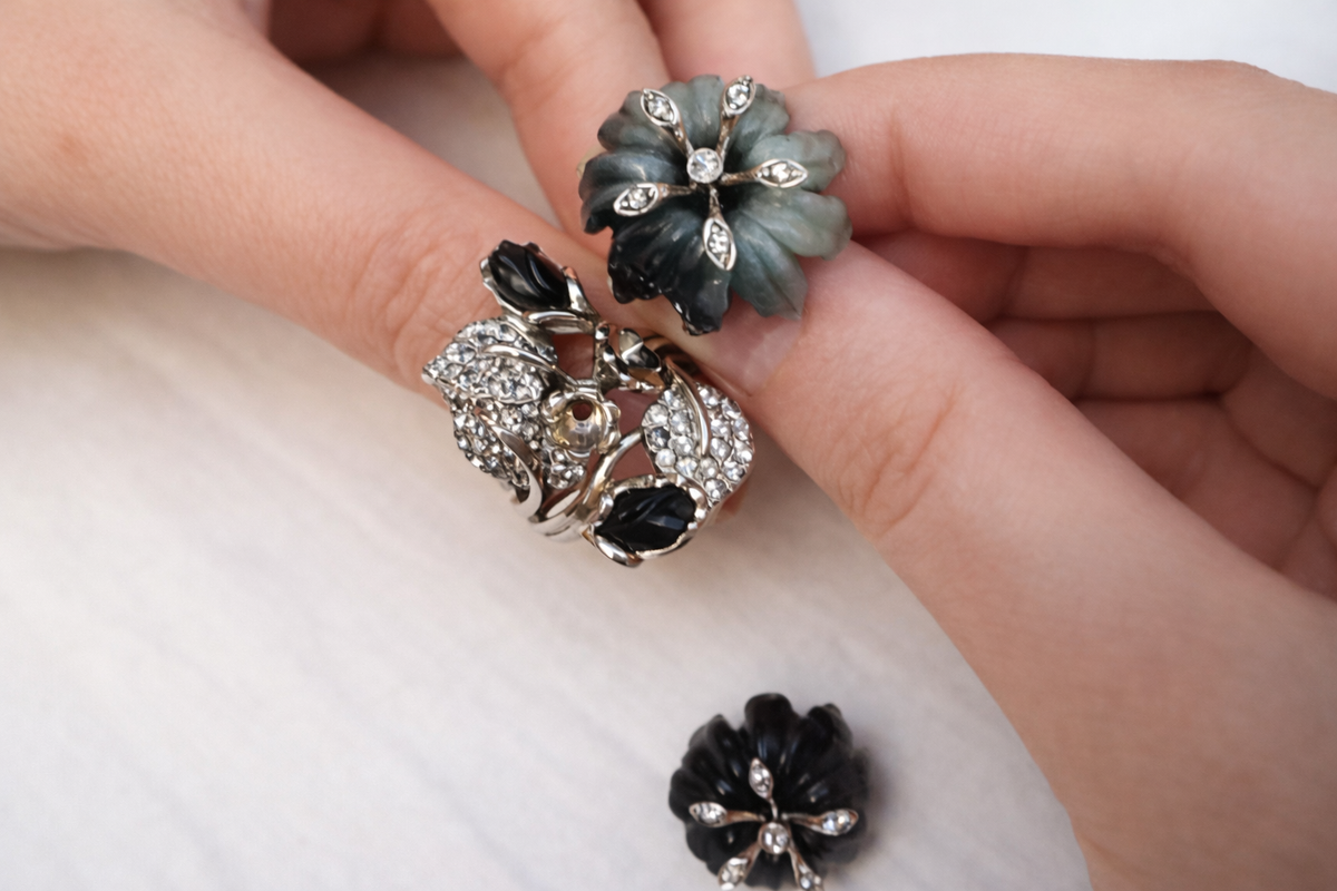 Asian Lily sculptural statement ring featuring carved cat's eye flowers and grey sapphires in 18K white gold, photographed on a hand.