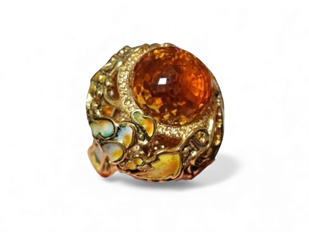 Close-up image of the Autumn Ring focusing on the intricate carving of the 33ct Madeira citrine briolette, the vivid hot enamel painting, and the yellow sapphires placed beneath the gemstone.