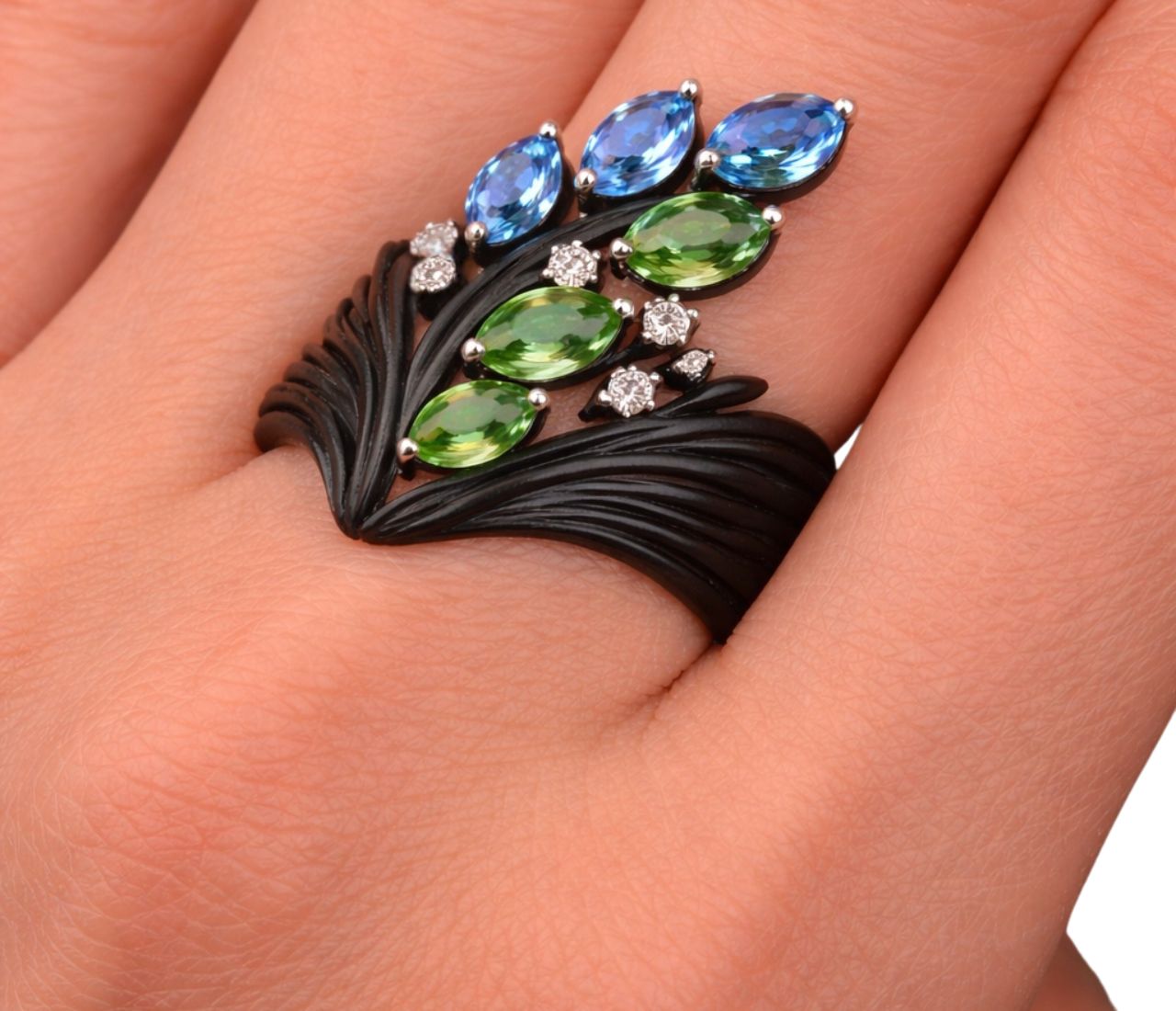 Ebony wood and gemstone statement ring worn on hand, featuring tsavorites, blue topaz and diamonds in 18K gold