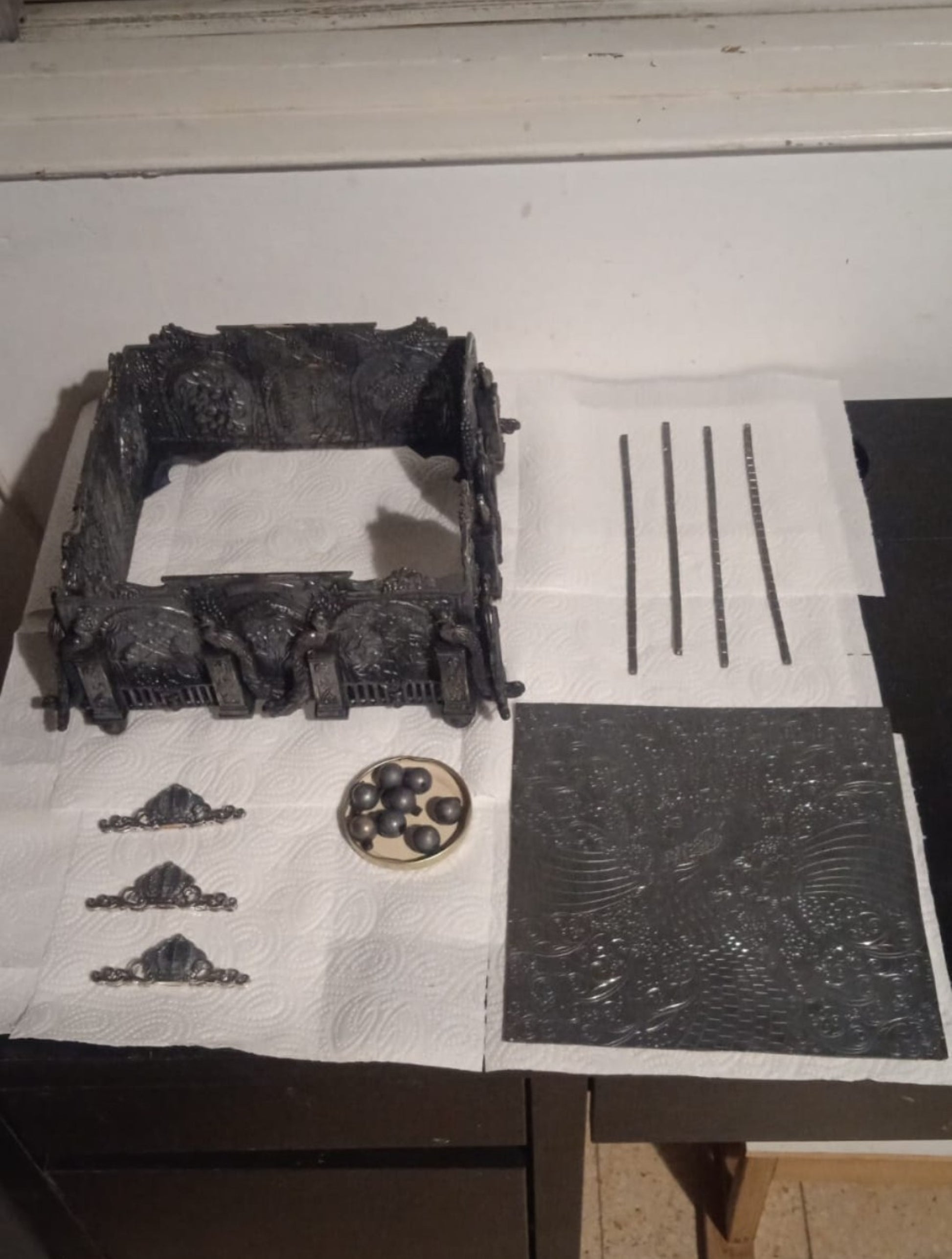Eden Palace sterling silver napkin holder during handcrafted production process showing assembled silver panels, engraved components, decorative mounts, and atelier craftsmanship.