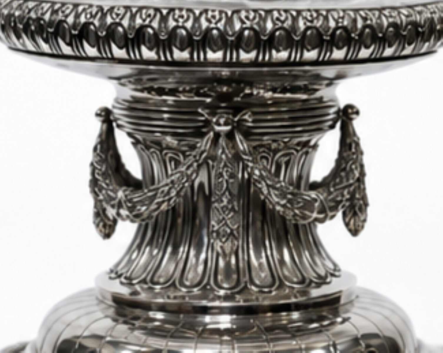 Close-up of the sculptural sterling silver column featuring engraved garlands and classical decorative elements beneath a crystal centerpiece bowl.