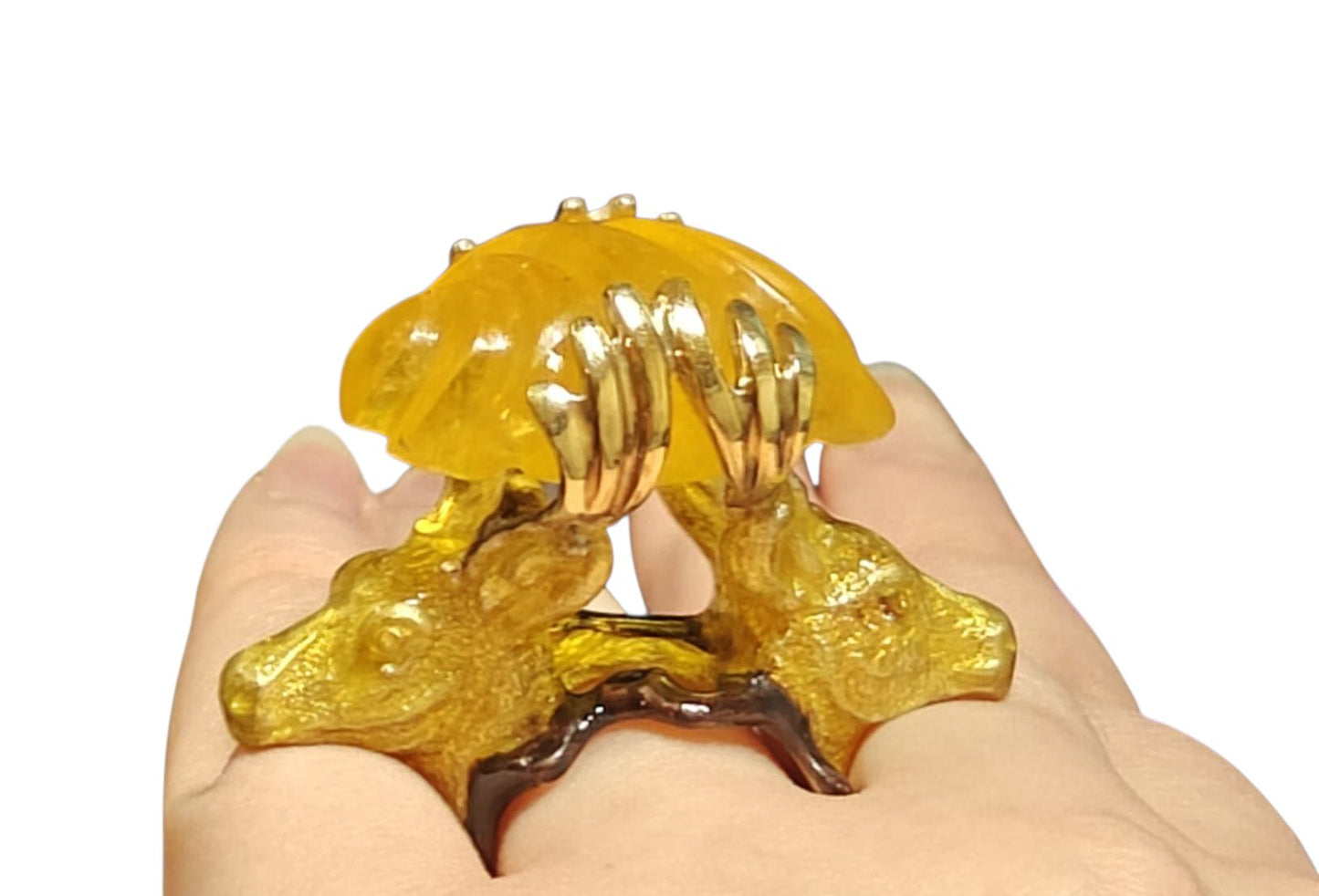 Guardians of the Sun ring by Konforti Jewelry shown on hand, handcrafted in 960 silver with sculpted stag figures holding a hand-carved 90 ct yellow lepidolite gemstone; detailed hot enamel artwork from the Stone Garden Collection.