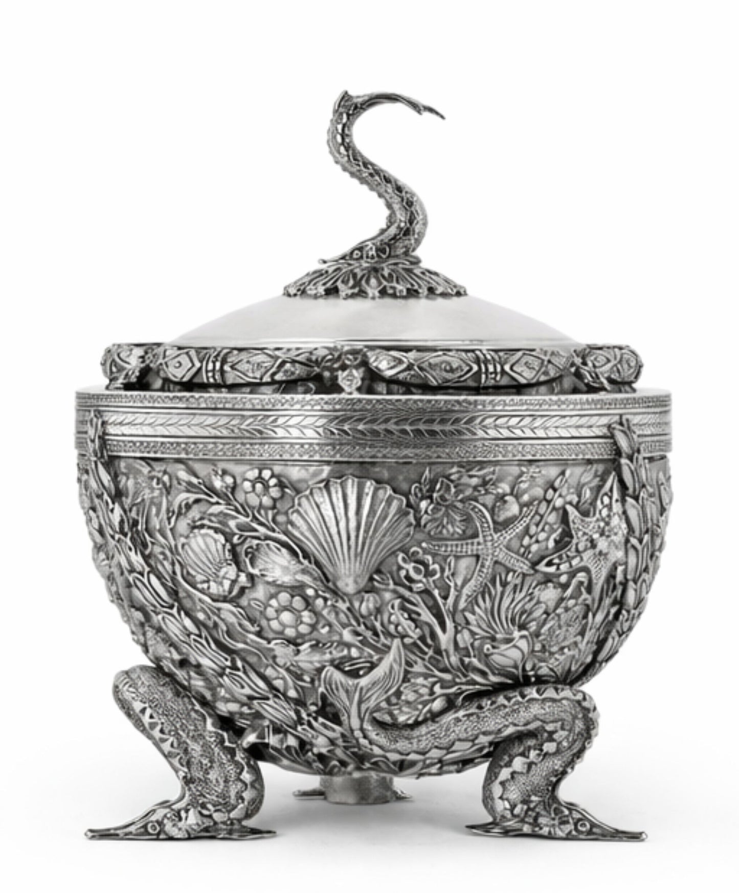 An ornate silver-toned lidded container or candelabra with intricate relief carvings of floral and marine motifs, featuring a sculpted snake handle on the lid and three detailed feet, shown against a plain white background.