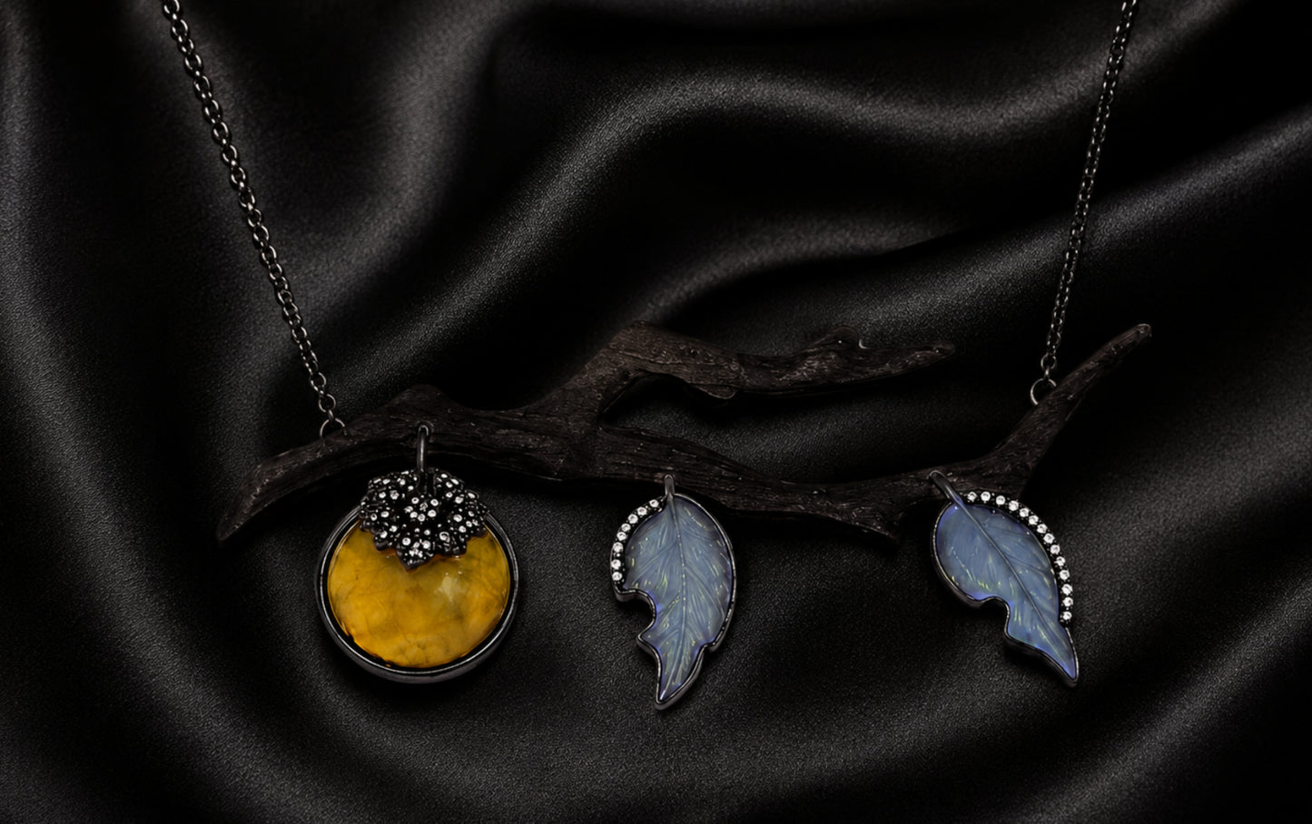 Close-up of artisanal persimmon pendant necklace with carved golden lepidolite fruit, angelite leaves, diamond accents, and ebony branch.