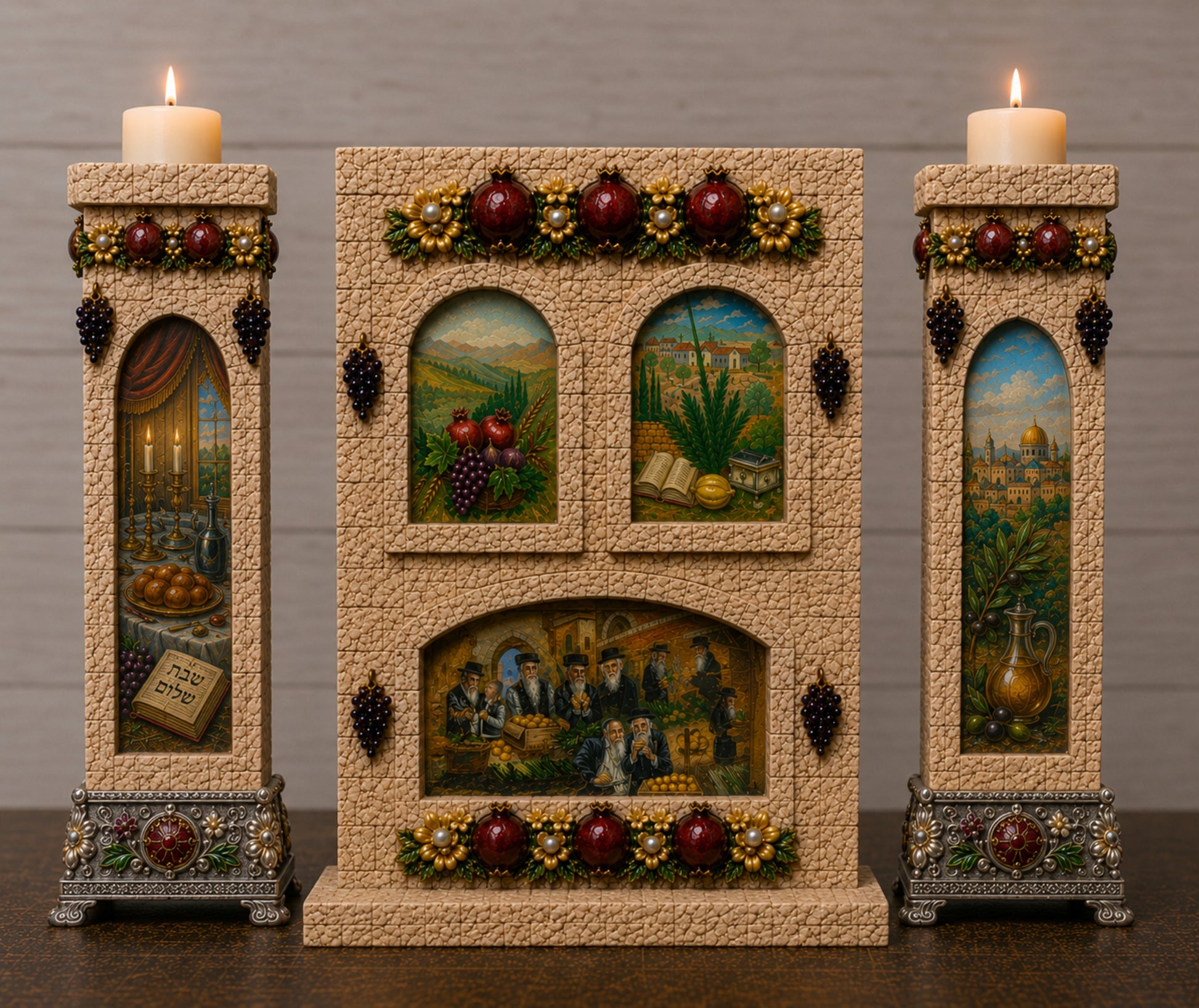 A decorative three-piece Judaica set featuring a central Passover Seder plaque flanked by two matching candle holders, all with detailed painted scenes, grapes, and lit candles on a dark wooden surface against a gray wall.