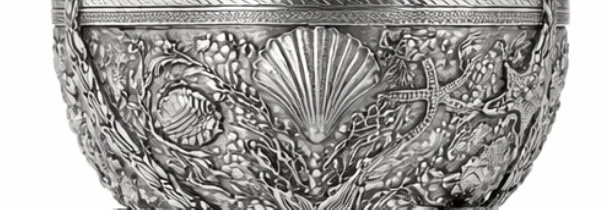 An ornate silver-toned metal bowl featuring intricate embossed sea-themed relief patterns including a scallop shell, starfish, and coral.