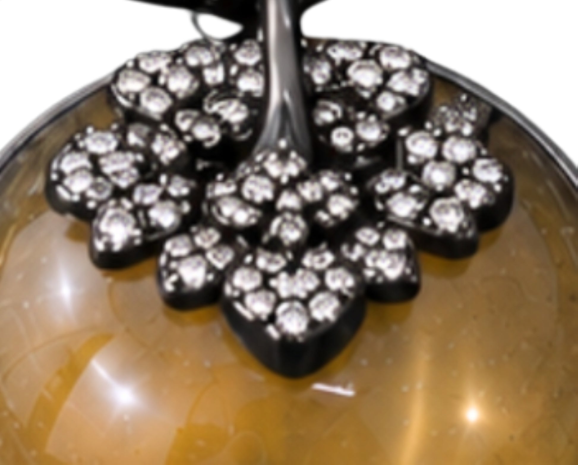 Macro view of pavé-set diamonds adorning the persimmon calyx and branch of the Golden Persimmon pendant in black rhodium-coated 18K gold.