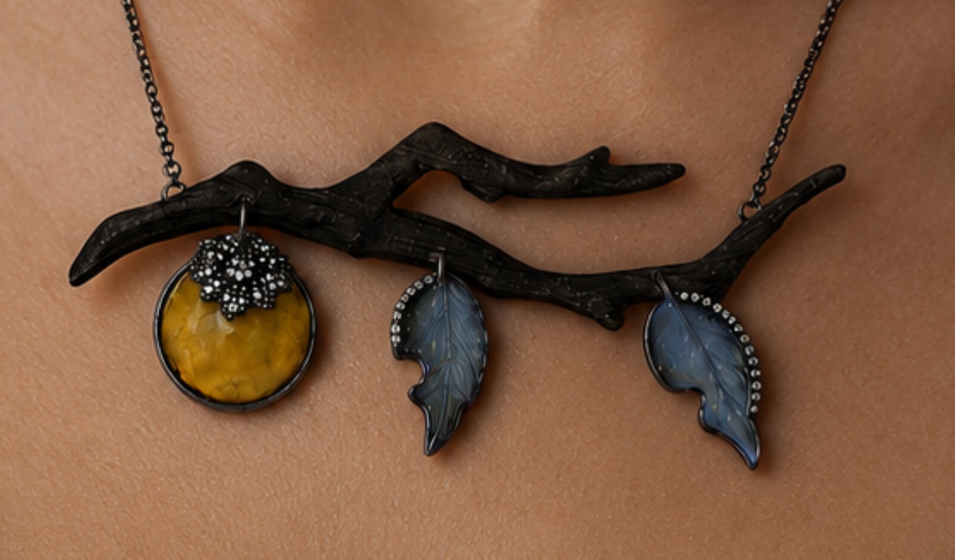 Close-up of artisanal persimmon pendant necklace with carved golden lepidolite fruit, angelite leaves, diamond accents, and ebony branch.