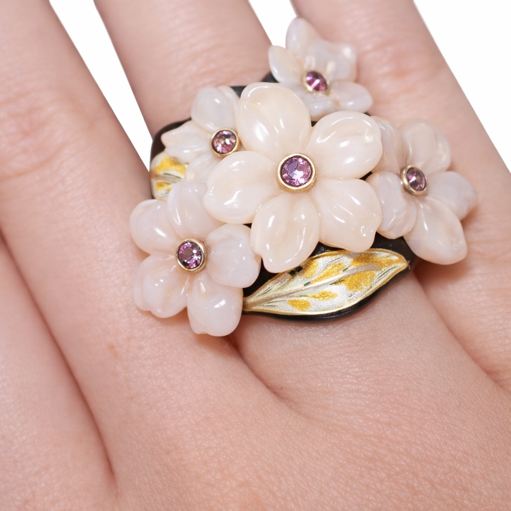 Close up of hand carved pink opal flower ring with round gold mounted pink sapphires and enamel leaf detail Konforti Jewelry