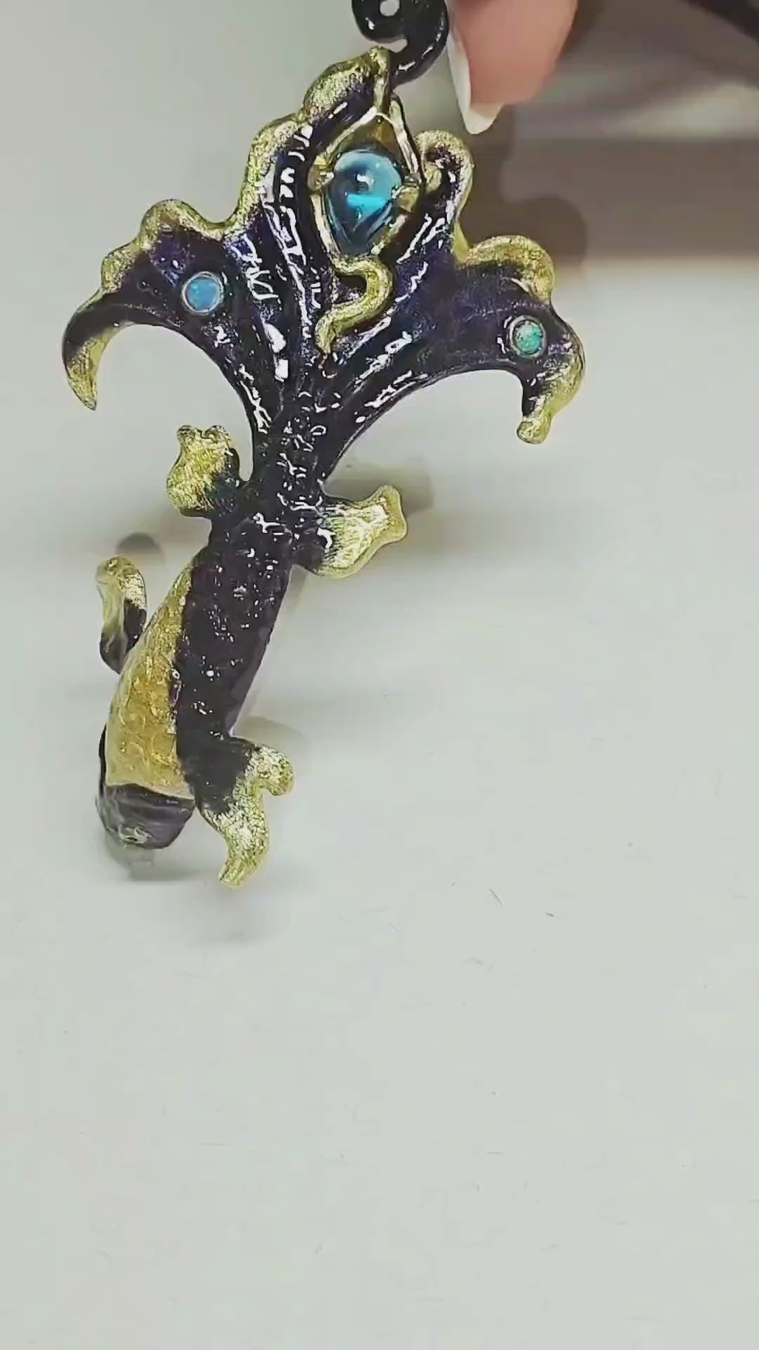 Close-up video of the Ocean Duet pendant from the Stone Garden Collection, showing the 960 silver craftsmanship, 3 ct blue topaz, 0.01 ct opal accents, and hand-painted Limoges hot enamel that creates layered ocean-wave colors. The camera moves to reveal depth, shimmer, and fine details of the sea-inspired design.