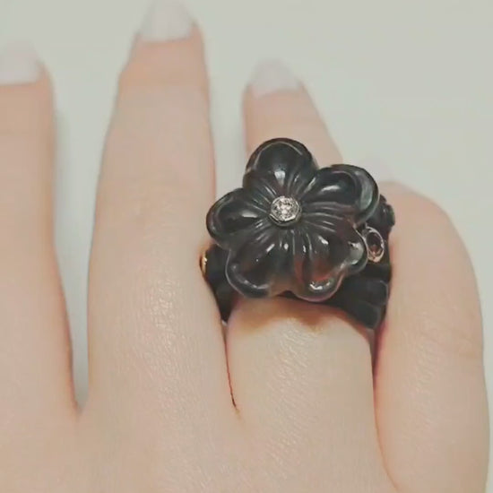Video of the Midnight Blossom ring from the Stone Garden Collection, showing the hand-carved 28ct smoky quartz flower set atop a 14K pink gold inner band and black ebony wood base. The rotating views highlight the diamond center, the 0.85ct tourmalines in the ring base, and the contrast between the carved gemstone and natural wood.