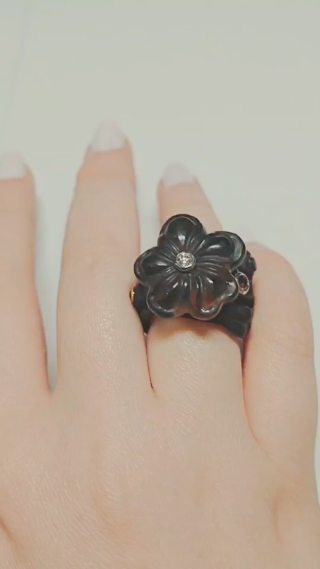 Video of the Midnight Blossom ring from the Stone Garden Collection, showing the hand-carved 28ct smoky quartz flower set atop a 14K pink gold inner band and black ebony wood base. The rotating views highlight the diamond center, the 0.85ct tourmalines in the ring base, and the contrast between the carved gemstone and natural wood.