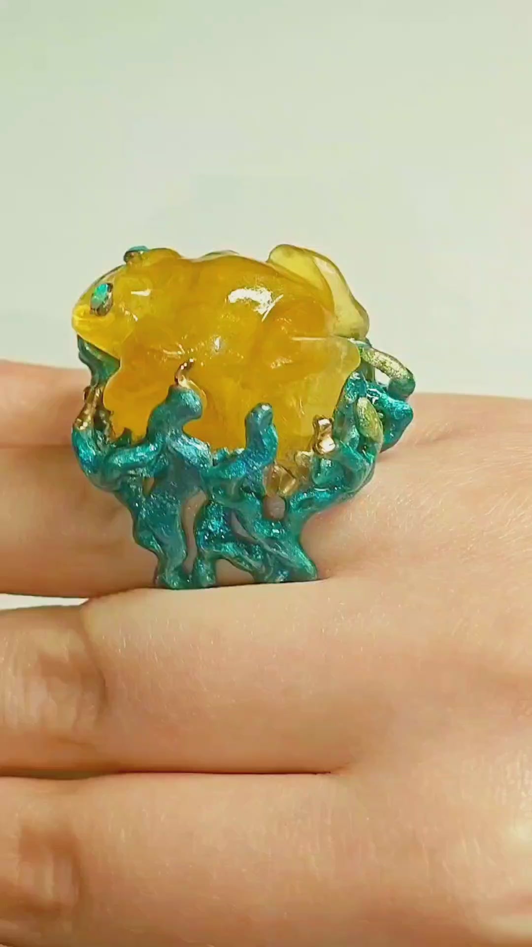 On-hand video of the Kelp Dancer ring, showcasing the 100 ct carved yellow lepidolite frog gemstone, 960 silver craftsmanship, opal eyes, and vivid Limoges-style hand-painted enamel from Konforti Jewelry’s Stone Garden Collection.