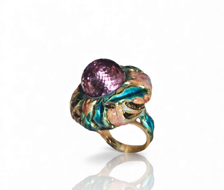 Angled studio view of the Purple Thistle ring displaying the dimensional amethyst briolette, vivid enamel artistry, and the white sapphire–set gold plate beneath the center stone.