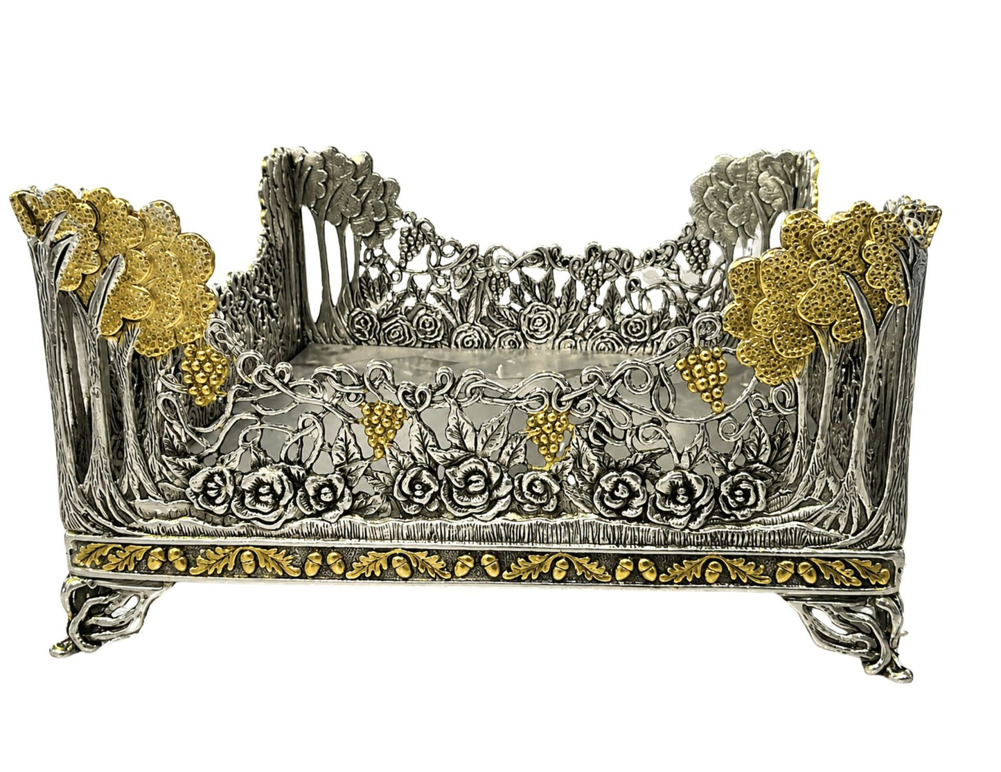 Three-quarter view of Royal Garden sterling silver and 18K gold napkin holder featuring sculpted roses, grape clusters, climbing vines, and gilded floral trees.