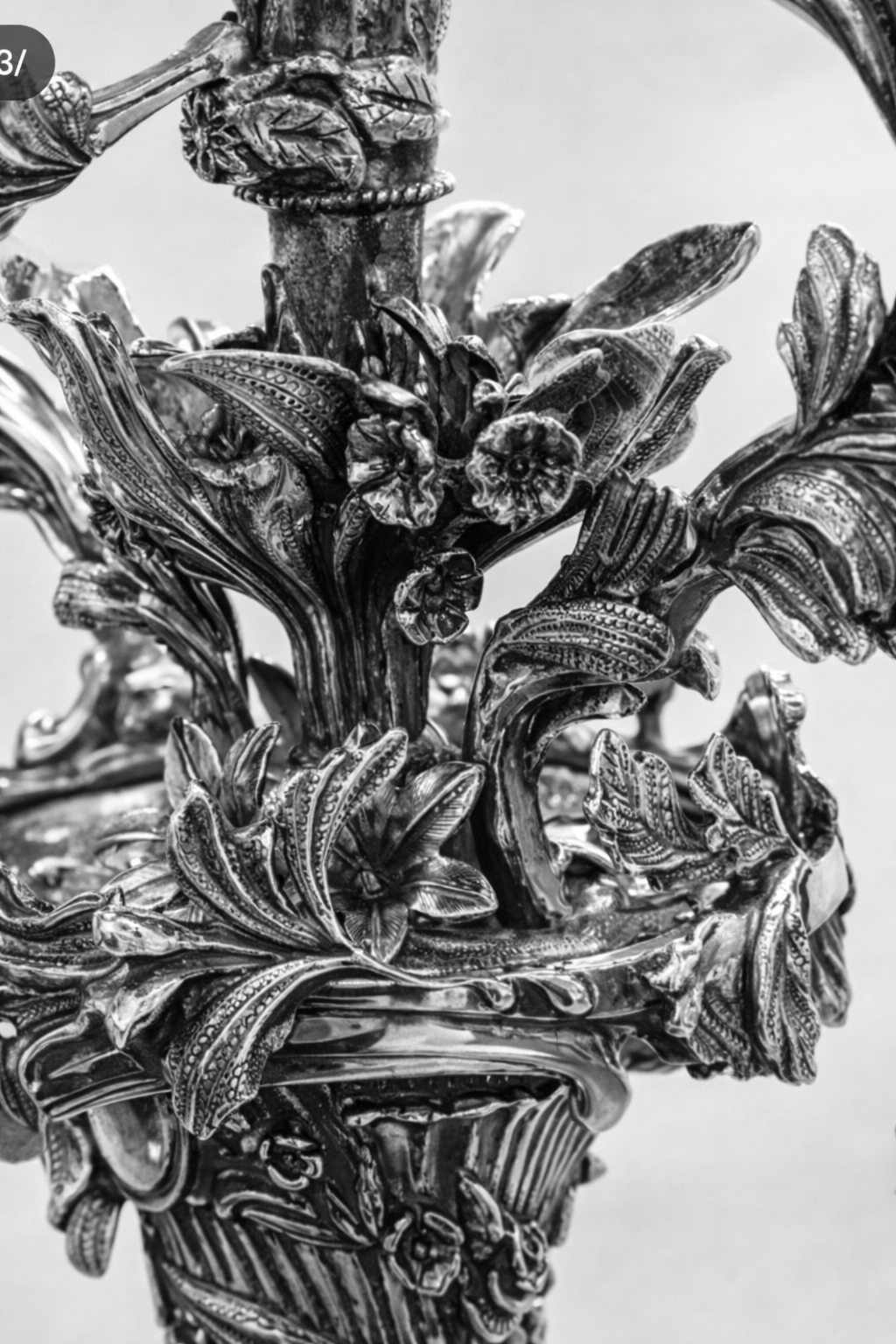 Ornate sterling silver menorah with flowing branches, floral elements, and intricate scrollwork forming a sculptural Judaica centerpiece