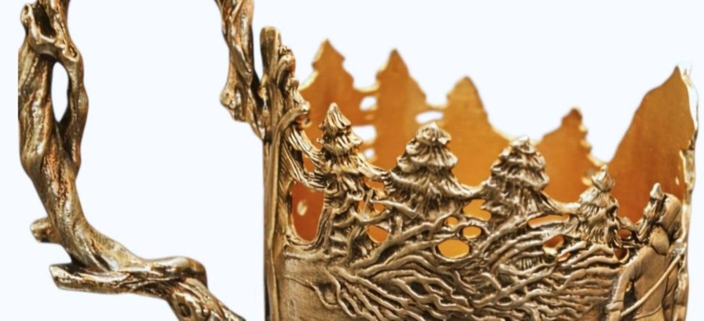 Close-up of sterling silver cup holder showing detailed winter forest relief with pine trees, moving figures, animals, and flowing snow landscape in narrative sculptural design