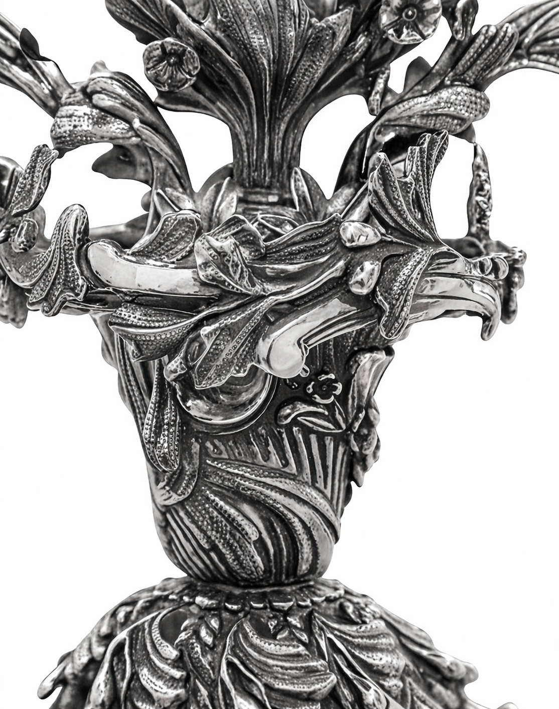 Close-up of handcrafted sterling silver menorah branches with detailed lily flowers and scrolling botanical ornamentation, hand chased and sculpted