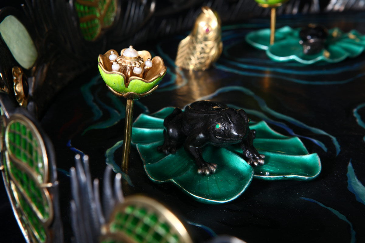 Close-up of a hand-carved frog resting on a lily pad in the “Summer Pond” centerpiece, sculpted from natural stone and solid silver with lifelike detail.
