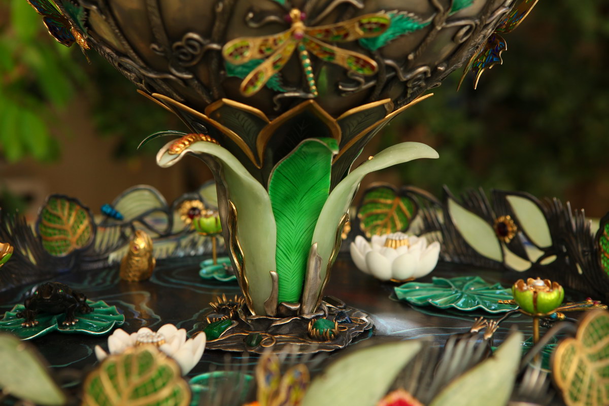 Lifestyle detail of the lower portion of the vase in the “Summer Pond” sculptural centerpiece, emphasizing silver engraving, gemstone inlays, and architectural depth.