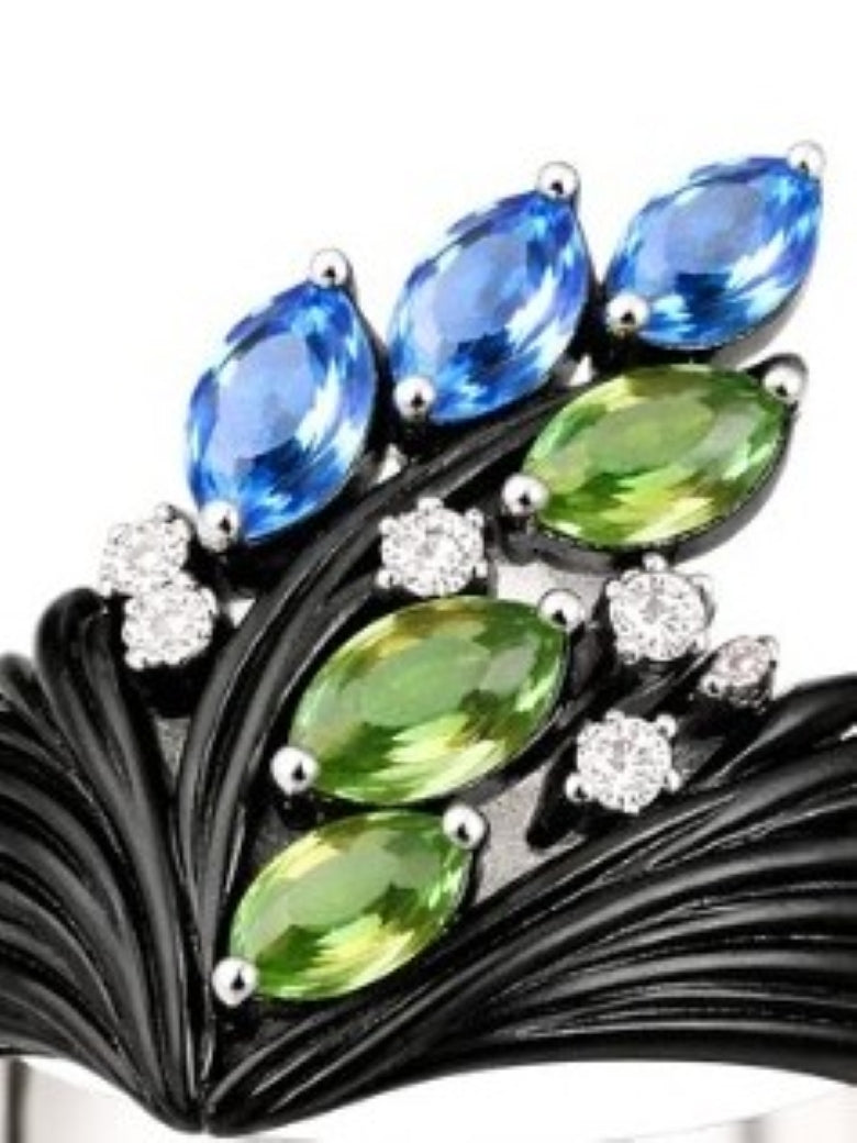 Close up of tsavorite, blue topaz and diamond setting in carved ebony wood ring with fine gold structure